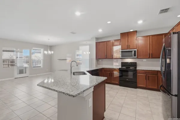 a kitchen with granite countertop a sink a counter top space appliances and cabinets