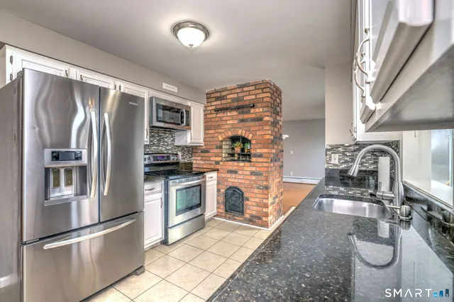a kitchen with stainless steel appliances granite countertop a refrigerator a stove and a sink