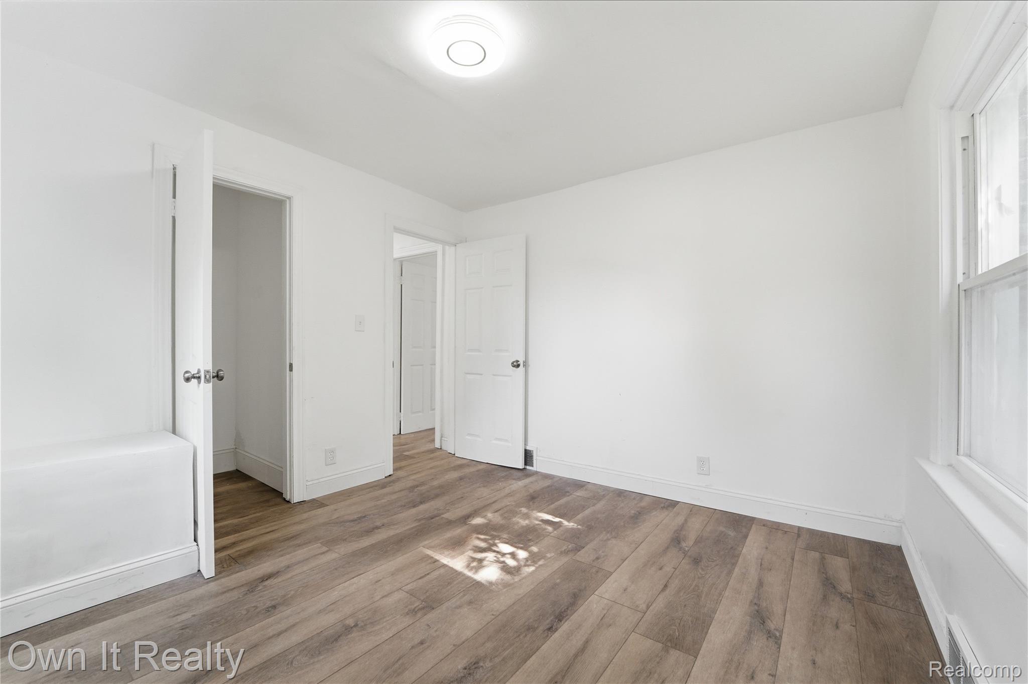 17351 Appoline Street Detroit, MI 48235 - Photo 26 of 34 Bright interior room featuring wood-finish flooring, white painted walls, a white baseboard trim, and a flush mount ceiling light fixture