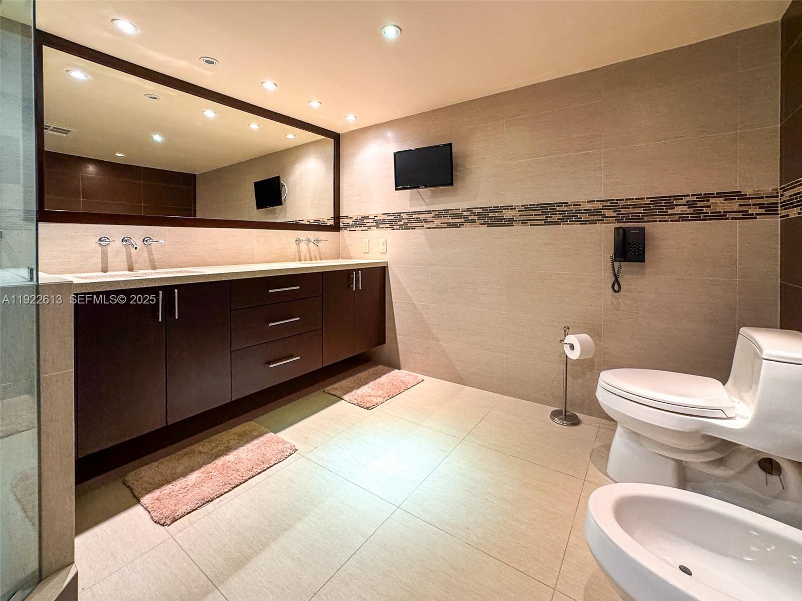 8877 Collins Avenue, Unit 809 Surfside, FL 33154 - Photo 25 of 46 a bathroom with a sink a toilet and a mirror