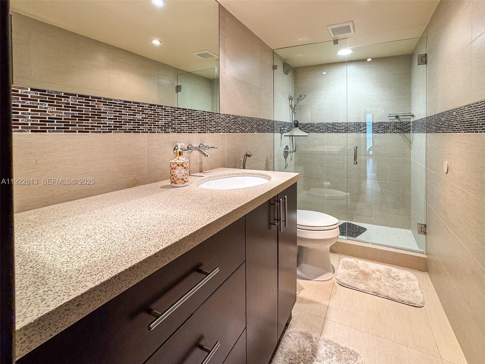 8877 Collins Avenue, Unit 809 Surfside, FL 33154 - Photo 29 of 46 a bathroom with a sink a toilet a mirror and shower