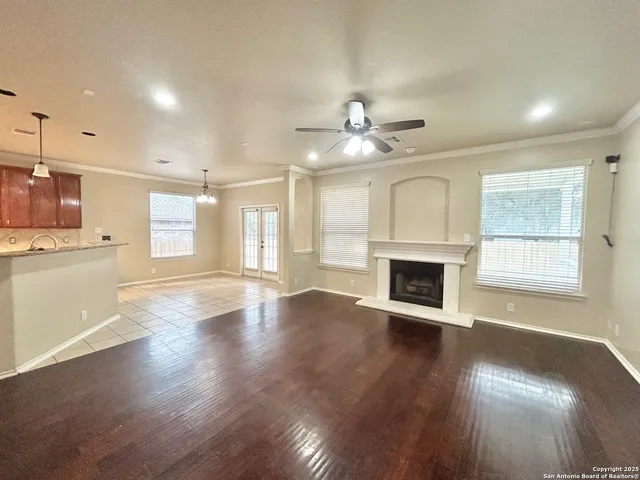 an empty room with wooden floor fireplace and windows