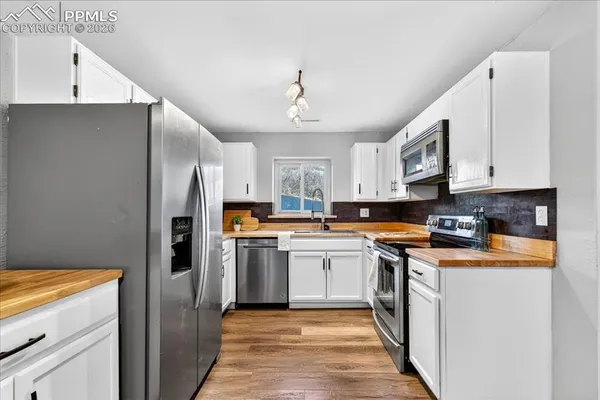 a kitchen with stainless steel appliances granite countertop a refrigerator a stove and a sink