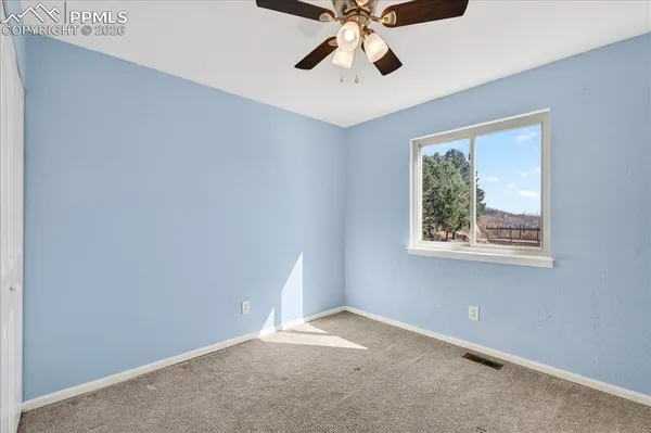 an empty room with a window and a fan
