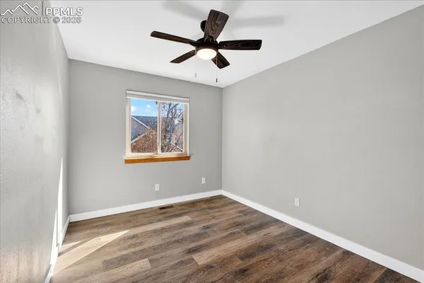 a view of an empty room with window and ceiling fan