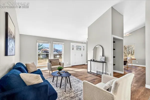 a living room with furniture a wooden floor and a large window