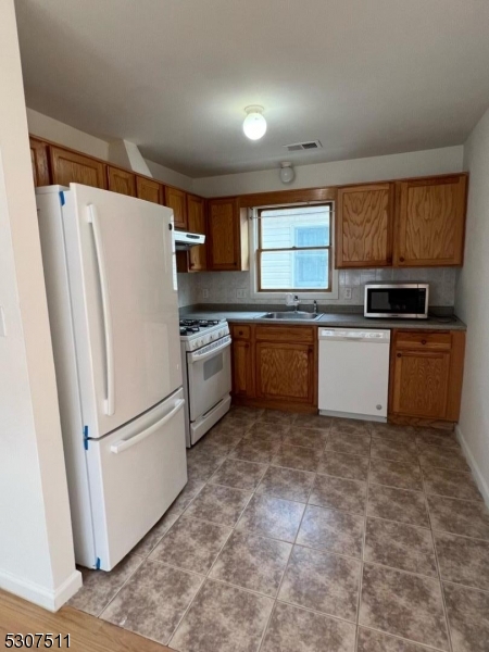 110 South 3rd Street Harrison, NJ 07029 - Photo 2 of 7 a kitchen with granite countertop a refrigerator stove top oven and sink
