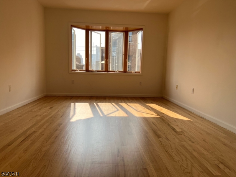 110 South 3rd Street Harrison, NJ 07029 - Photo 4 of 7 an empty room with wooden floor and windows