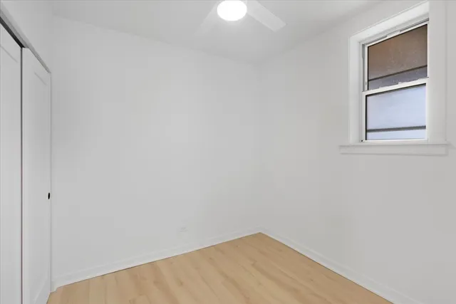a view of an empty room with closet and wooden floor