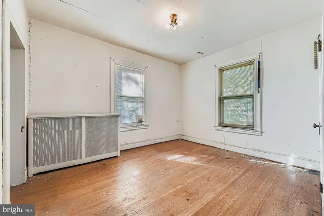 an empty room with wooden floor cabinet and windows