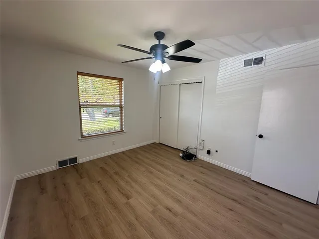 a view of an empty room and window with a ceiling fan