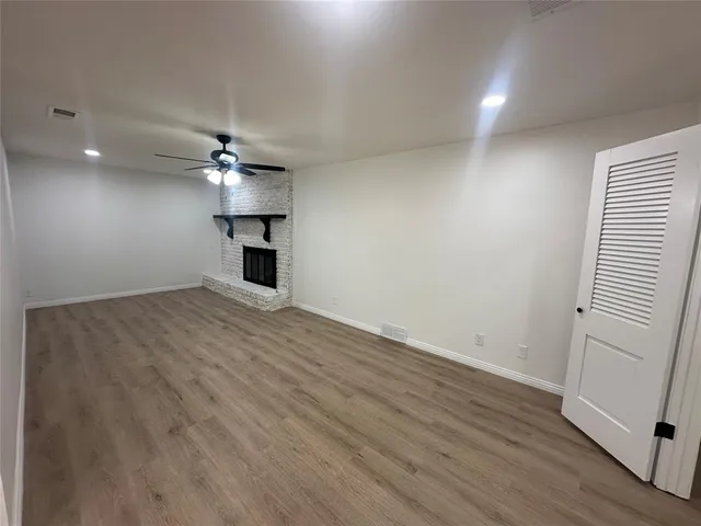 an empty room with wooden floor chandelier fan and windows