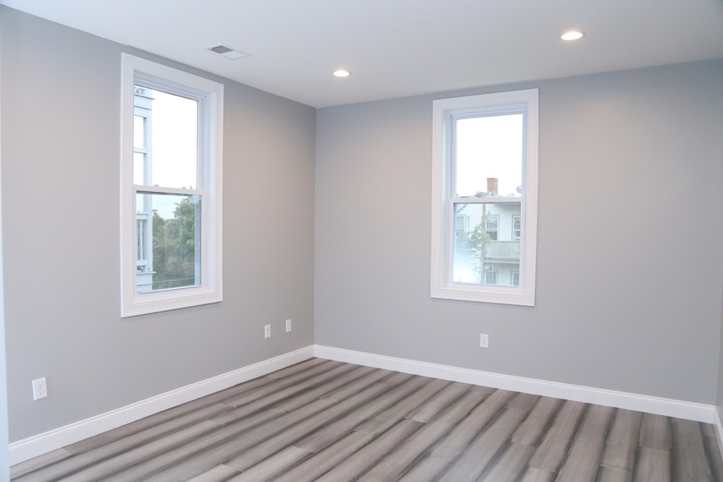 56 Byron Street, Unit 2 Boston, MA 02128 - Photo 13 of 17 an empty room with wooden floor and windows