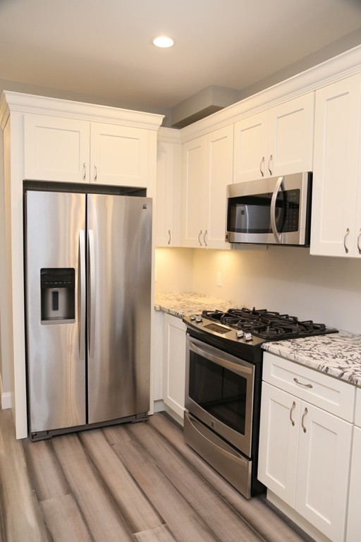 56 Byron Street, Unit 2 Boston, MA 02128 - Photo 3 of 17 a kitchen with granite countertop a refrigerator stove and microwave