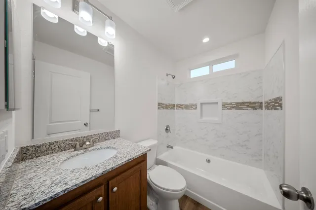 a bathroom with a granite countertop sink a toilet and bathtub