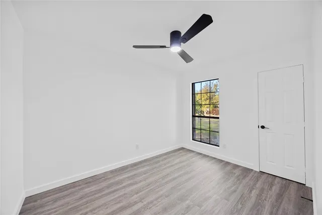 an empty room with wooden floor cabinet and windows