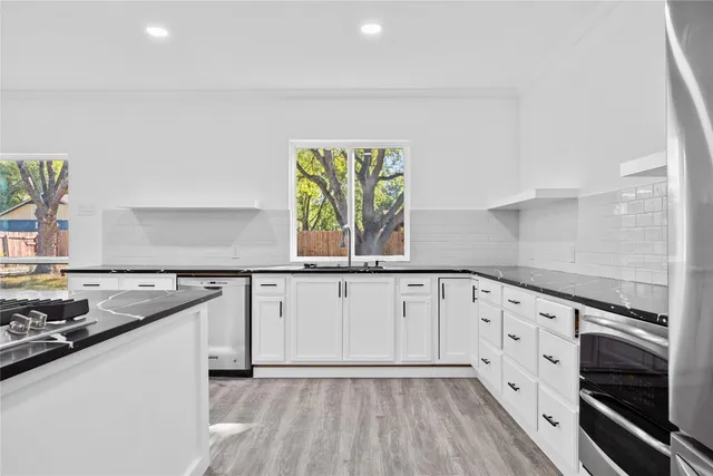 a kitchen with granite countertop white cabinets and a wooden floor