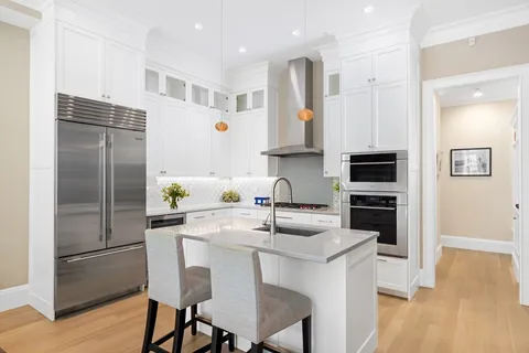a kitchen with stainless steel appliances a sink a stove a refrigerator cabinets and wooden floor