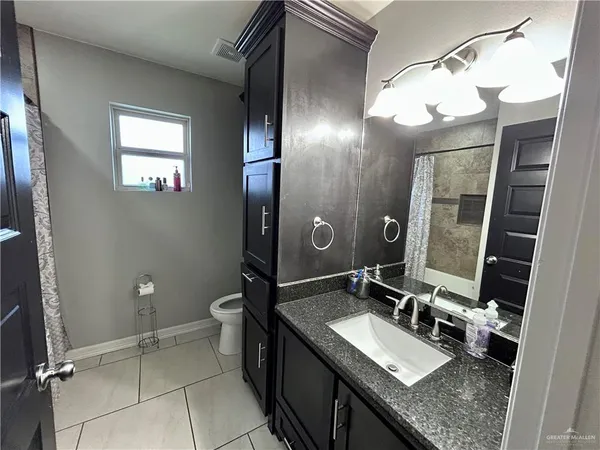 a bathroom with a granite countertop sink a mirror and a toilet
