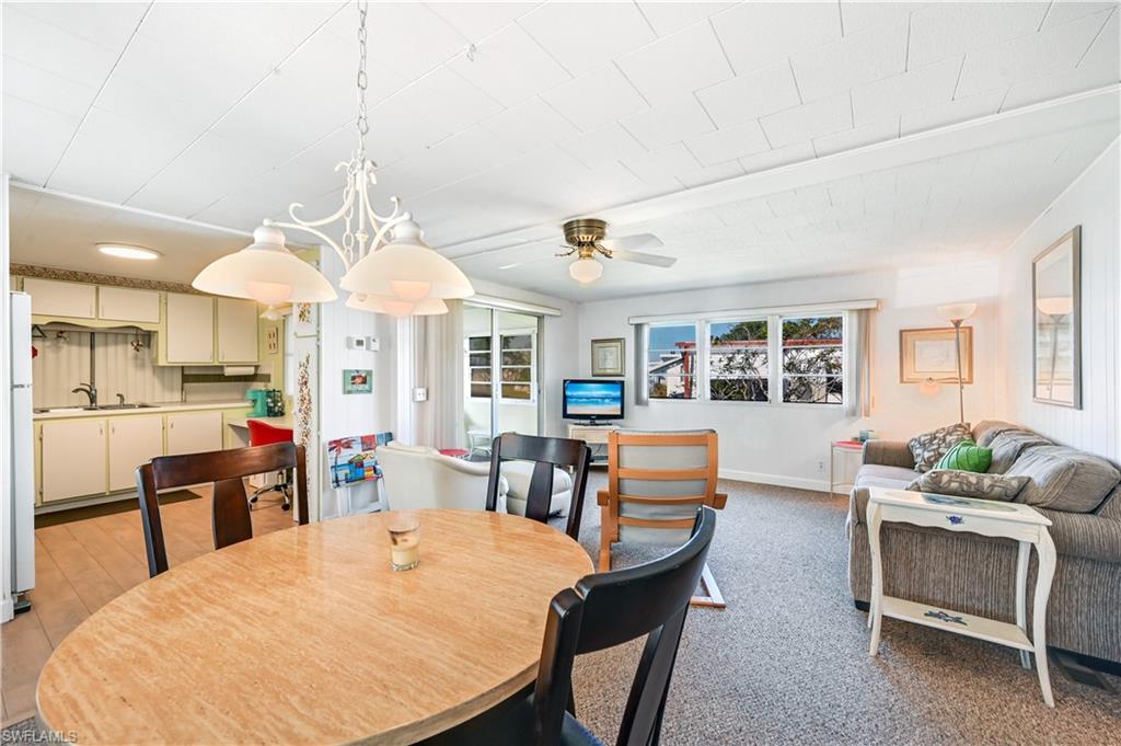 11 Moonstone Circle Naples, FL 34112 - Photo 6 of 20 a dining room with wooden floor a chandelier a wooden table and chairs
