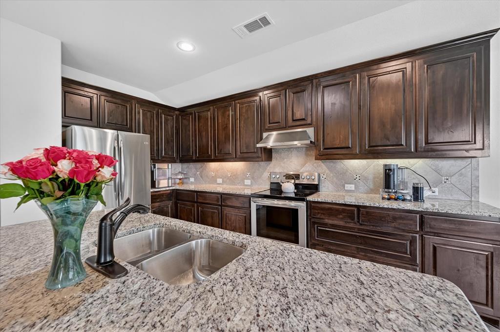 106 Zion Lane Forney, TX 75126 - Photo 11 of 37 a kitchen with granite countertop a sink stove and cabinets
