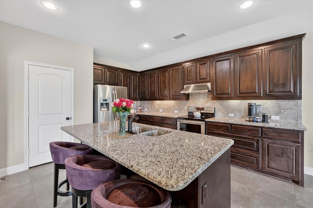 106 Zion Lane Forney, TX 75126 - Photo 9 of 37 a kitchen with granite countertop kitchen island stainless steel appliances a sink table and chairs