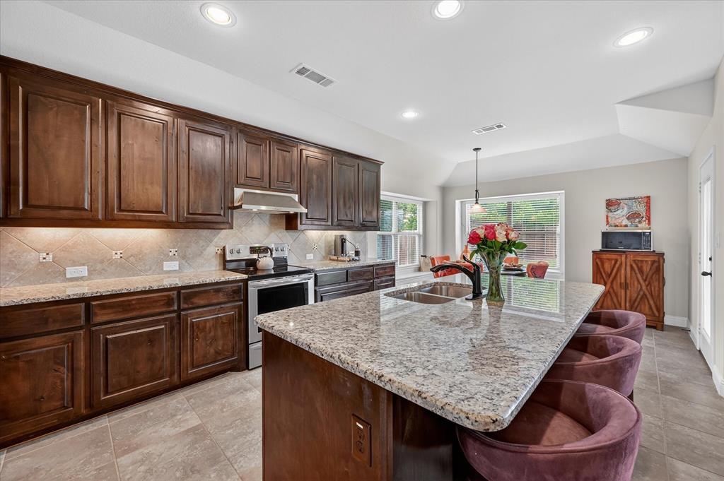 106 Zion Lane Forney, TX 75126 - Photo 10 of 37 a kitchen with granite countertop sink and wooden cabinets