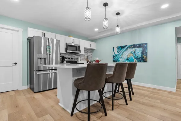 a kitchen with stainless steel appliances granite countertop a refrigerator a stove top oven a sink dishwasher a dining table and chairs with wooden floor