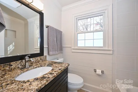 a bathroom with a granite countertop toilet a sink and a mirror
