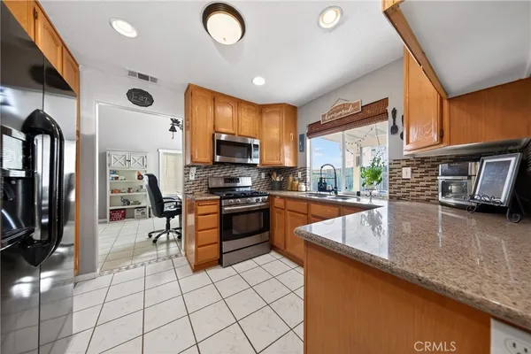 a kitchen with stainless steel appliances granite countertop a sink a stove counter space and cabinets