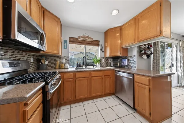 a kitchen with stainless steel appliances granite countertop a stove top oven a sink dishwasher and cabinets with wooden floor