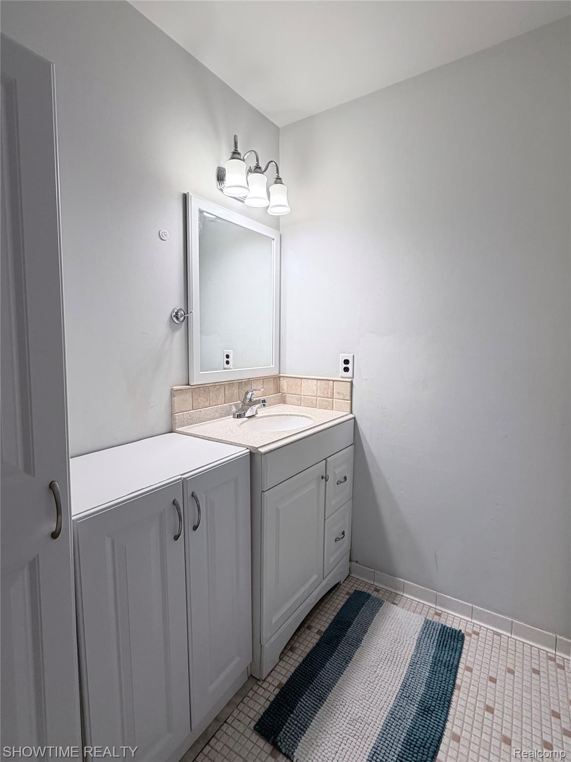 29117 Hayes Road, Unit 3 Warren, MI 48088 - Photo 13 of 14 White vanity with integrated sink, light-colored countertop, and tiled backsplash