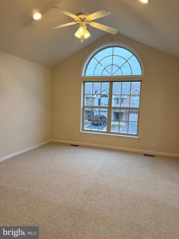 an empty room with a fan & a window