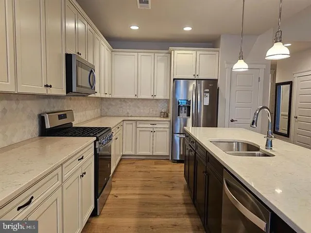 a kitchen with stainless steel appliances sink stove refrigerator and cabinets