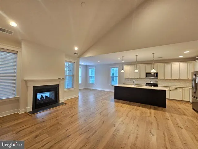 a large kitchen with stainless steel appliances a large kitchen island a hardwood floor sink and stove