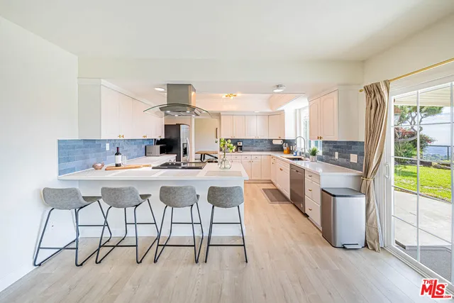 a kitchen with stainless steel appliances kitchen island granite countertop a stove a sink and white cabinets with wooden floor