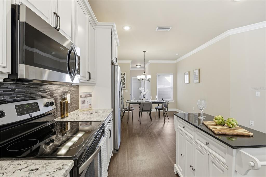 7894 Southwest 80th Drive Gainesville, FL 32608 - Photo 13 of 31 a kitchen with stainless steel appliances kitchen island granite countertop a stove a sink and a microwave
