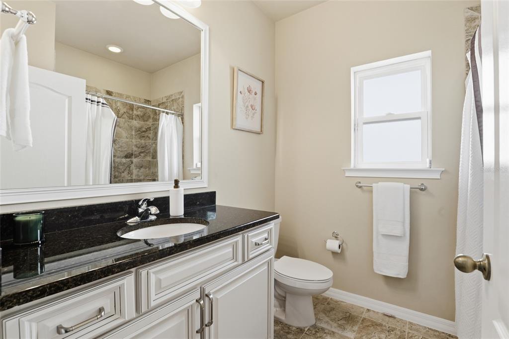 7894 Southwest 80th Drive Gainesville, FL 32608 - Photo 23 of 31 a bathroom with a granite countertop toilet a sink a mirror and a window