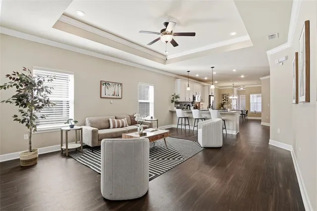 a living room with couches and kitchen view with wooden floor