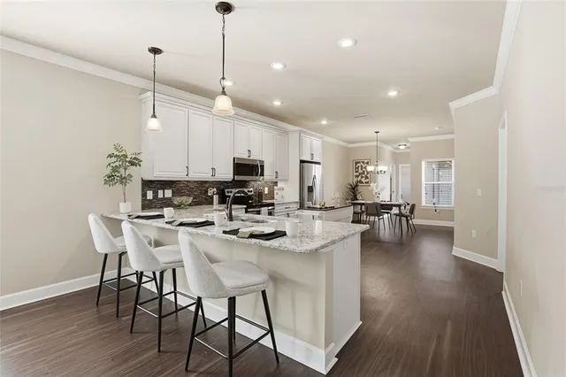 a kitchen with stainless steel appliances kitchen island granite countertop a stove a sink a dining table and chairs with wooden floor