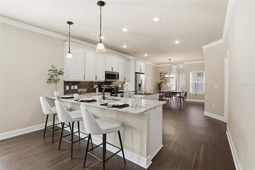 7894 Southwest 80th Drive Gainesville, FL 32608 - Photo 9 of 31 a kitchen with stainless steel appliances kitchen island granite countertop a stove a sink a dining table and chairs with wooden floor