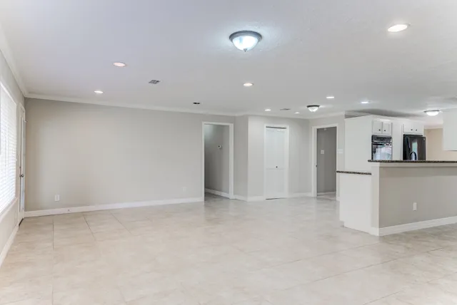 an empty room with kitchen view and a refrigerator