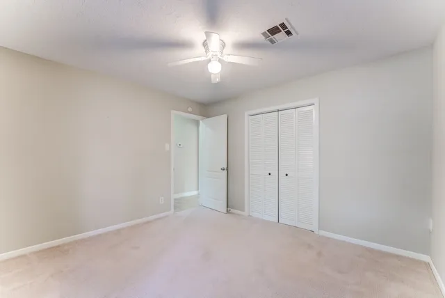 a view of an empty room and a chandelier fan