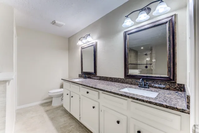 a bathroom with a granite countertop double vanity sink and a mirror