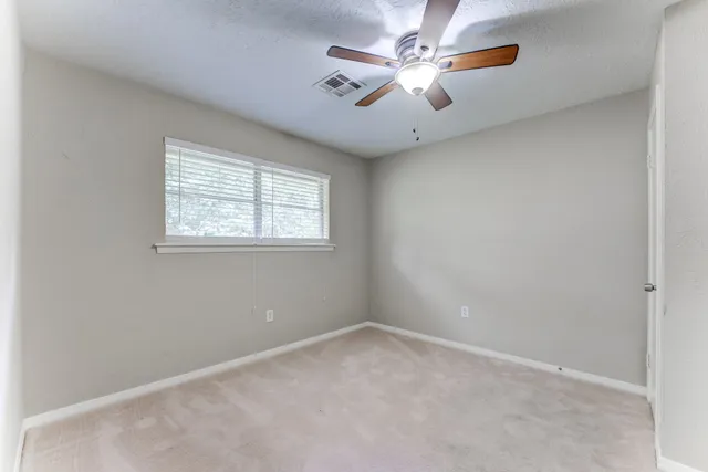 an empty room with a window and a fan