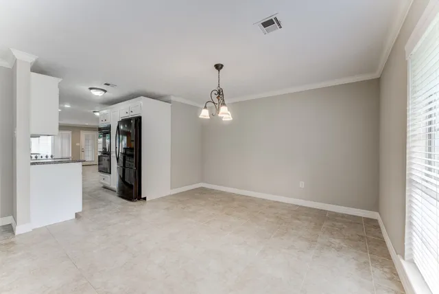 a view of an empty room with kitchen view and a window