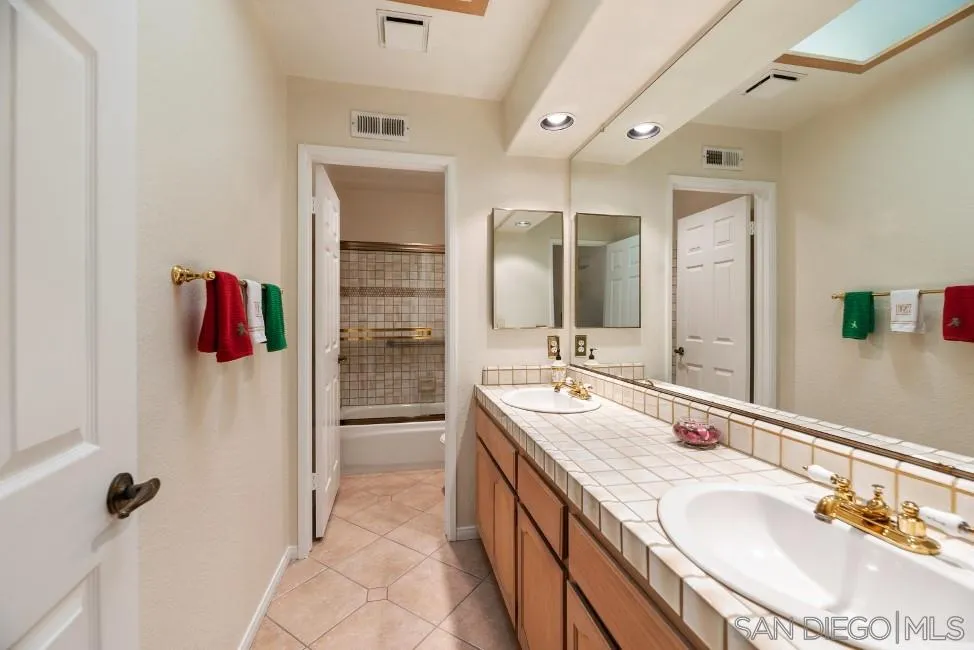 13873 Carriage Road Poway, CA 92064 - Photo 22 of 32 a bathroom with a granite countertop sink mirror and shower