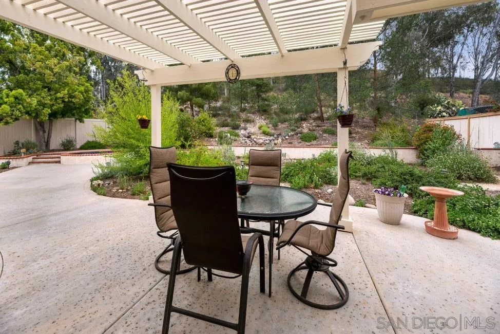 13873 Carriage Road Poway, CA 92064 - Photo 28 of 32 a view of a patio with table and chairs potted plants and a large tree