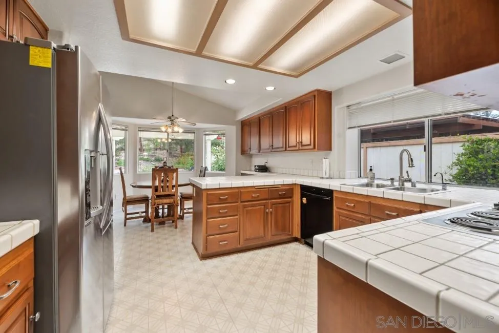 13873 Carriage Road Poway, CA 92064 - Photo 5 of 32 a kitchen with stainless steel appliances kitchen island granite countertop a table chairs sink and cabinets