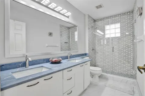 a bathroom with a granite countertop sink mirror vanity and toilet